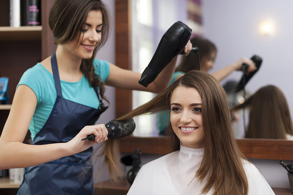 Female hairdresser using hairbrush and hair dryer Female hairdresser using hairbrush and hair dryer